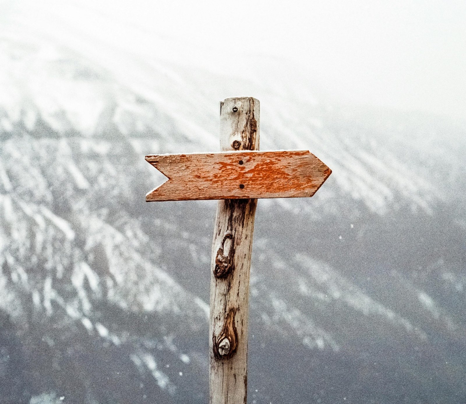 pexels-photo-66100-66100 A wooden arrow signpost points the way amidst a snowy mountain landscape.